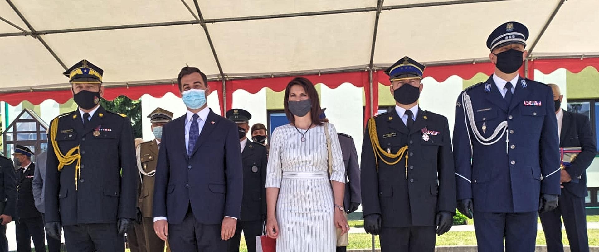 Pod namiotem w kolorze białym w szeregu stoją: Komendant Główny PSP nadbrygadier Arkadiusz Przybyła. Sekretarz Stanu w Kancelarii Prezydenta RP Błażej Spychalski, Posłowie na Sejm RP: Ewa Kozanecka i Piotr Król, Komendant Wojewódzki st. bryg. Jacek Kaczmarek, Komendant Szkoły Podoficerskiej PSP w Bydgoszczy st. bryg. Jacek Antos oraz przedstawiciele innych służb mundurowych.