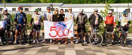 Zdjęcie przedstawia strażaków kolarzy z rowerami oraz logiem 500+ km. 