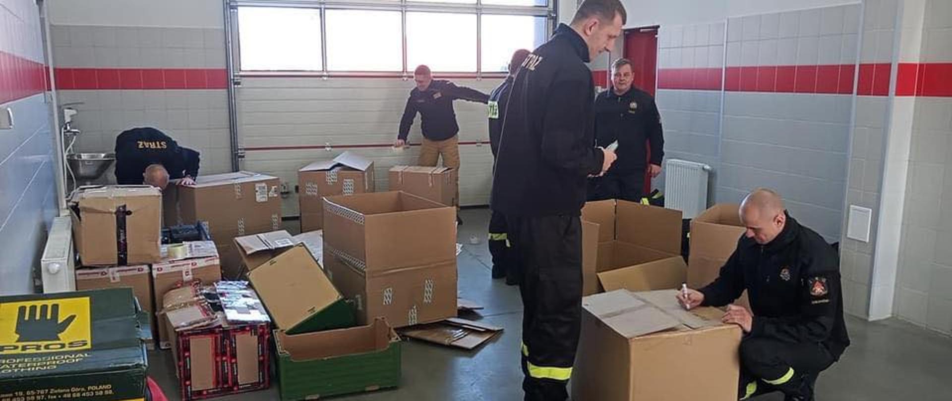 Na zdjęciu strażacy w garażu Komendy przygotowujący przesyłki humanitarne dla ludności Ukrainy oraz funkcjonariuszy ukraińskiej straży pożarnej.