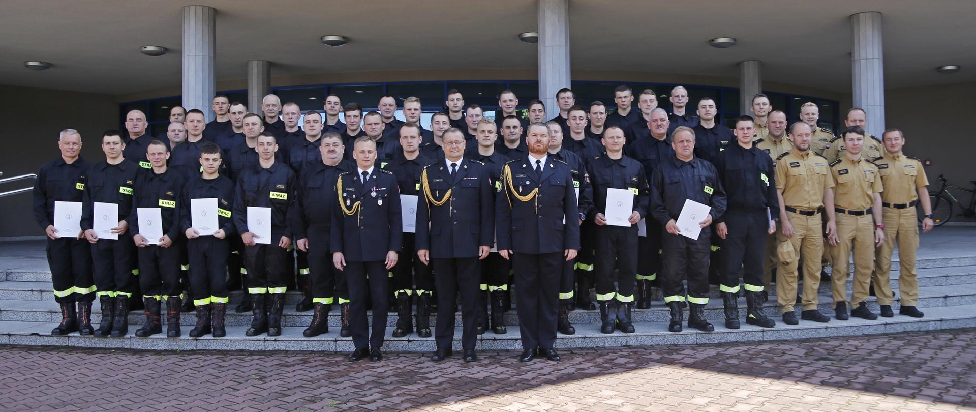 Grupowe zdjęcie strażaków pierwszego turnusu Szkolenia Podstawowego w Zawodzie Strażaka w towarzystwie Zastępców Komendanta Centralnej Szkoły PSP oraz funkcjonariuszy wydziału nauczania CS PSP
