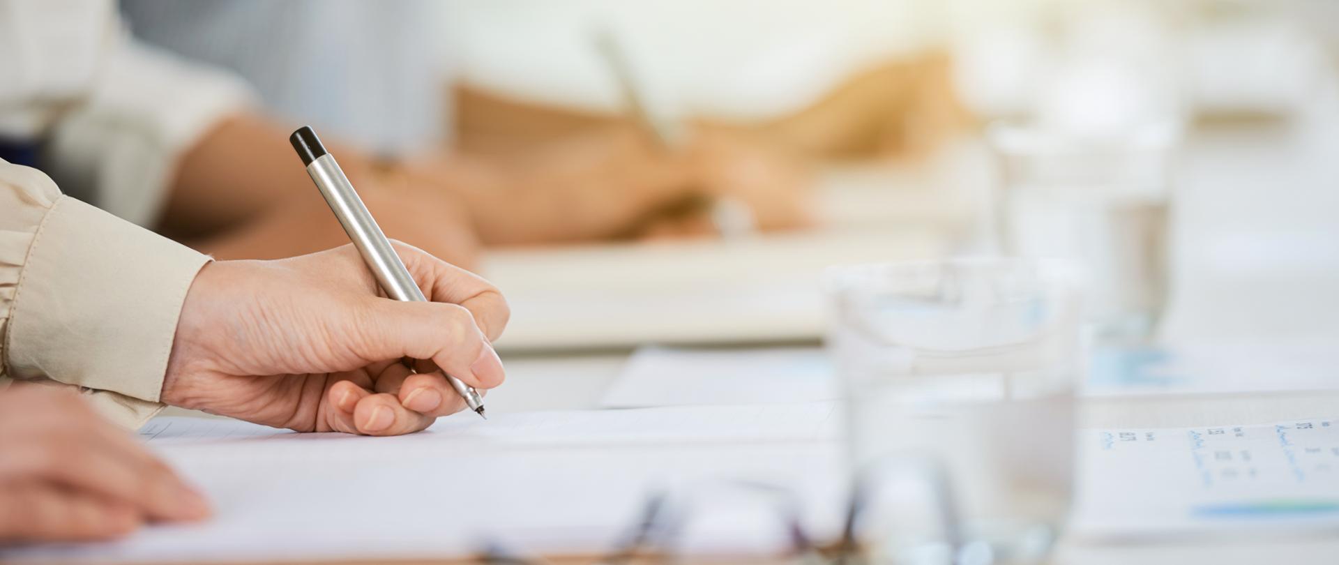 Hand of business lady signing agreement at meeting