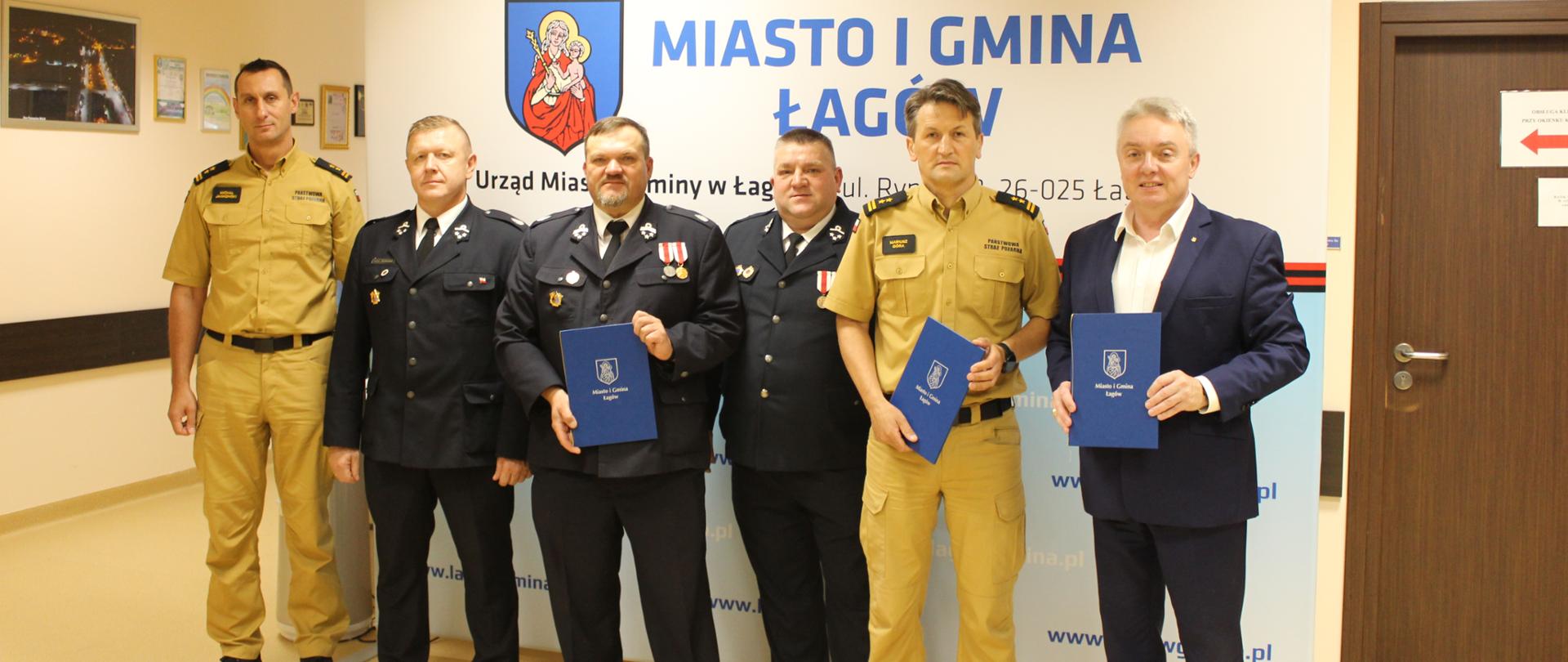 Zdjęcie przedstawia uczestników spotkania stojących na tle ściany z logo i nazwą Łagowa.