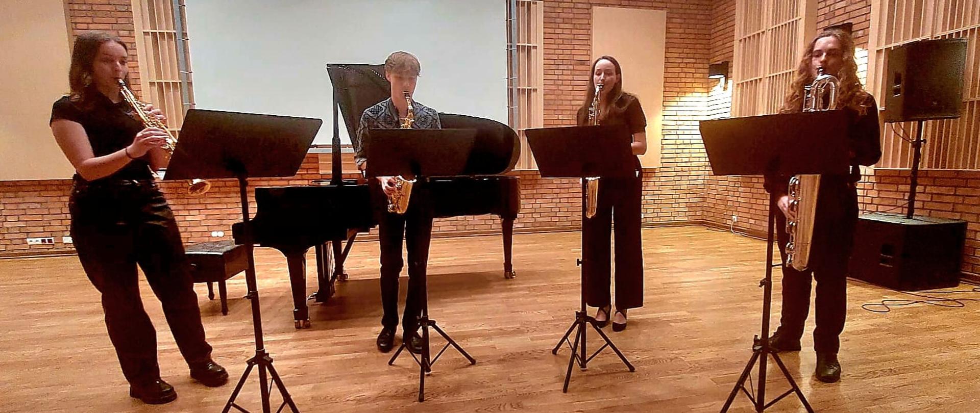 Przed pulpitami czworo uczniów - kwartet saksofonowy 
