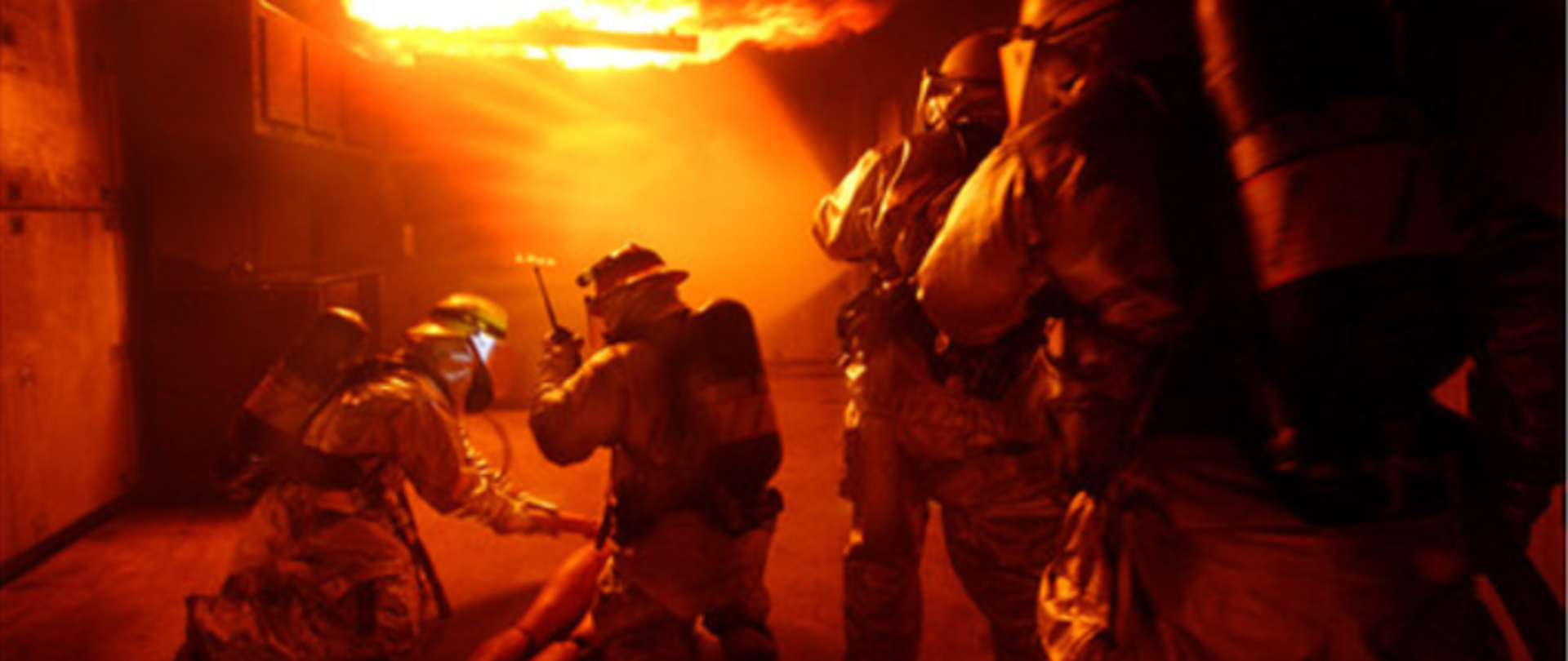 Zdjęcie przedstawia czterech strażaków podczas ćwiczeń praktycznych w zakresie działań gaśniczych oraz ewakuacji osoby poszkodowanej
