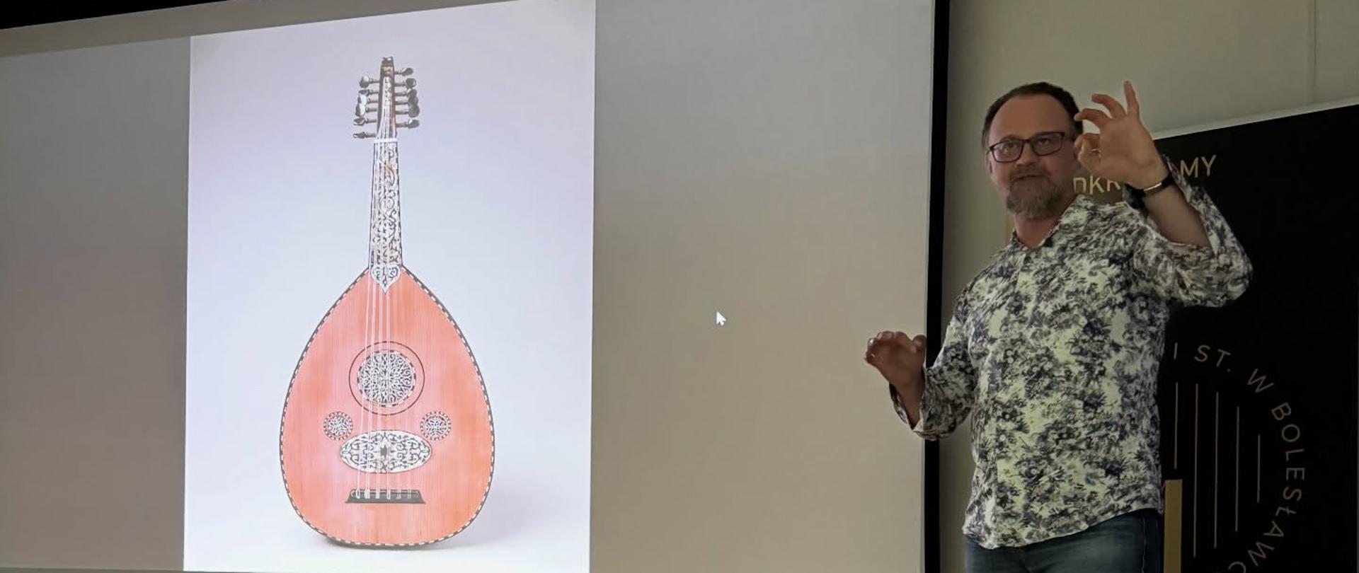 Zdjęcie przedstawiające prowadzących prelekcję multimedialną o historii gitary, która odbyła się 24 lutego 2026 roku w auli szkoły. Prelekcję prowadzili nauczyciele klasy gitary - pan Sebastian Środa oraz pan Bartłomiej Filipowicz.