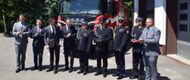 politycy, strażacy, druhowie i samorządowcy pozują do zdjęcia na tle samochodu gaśniczego