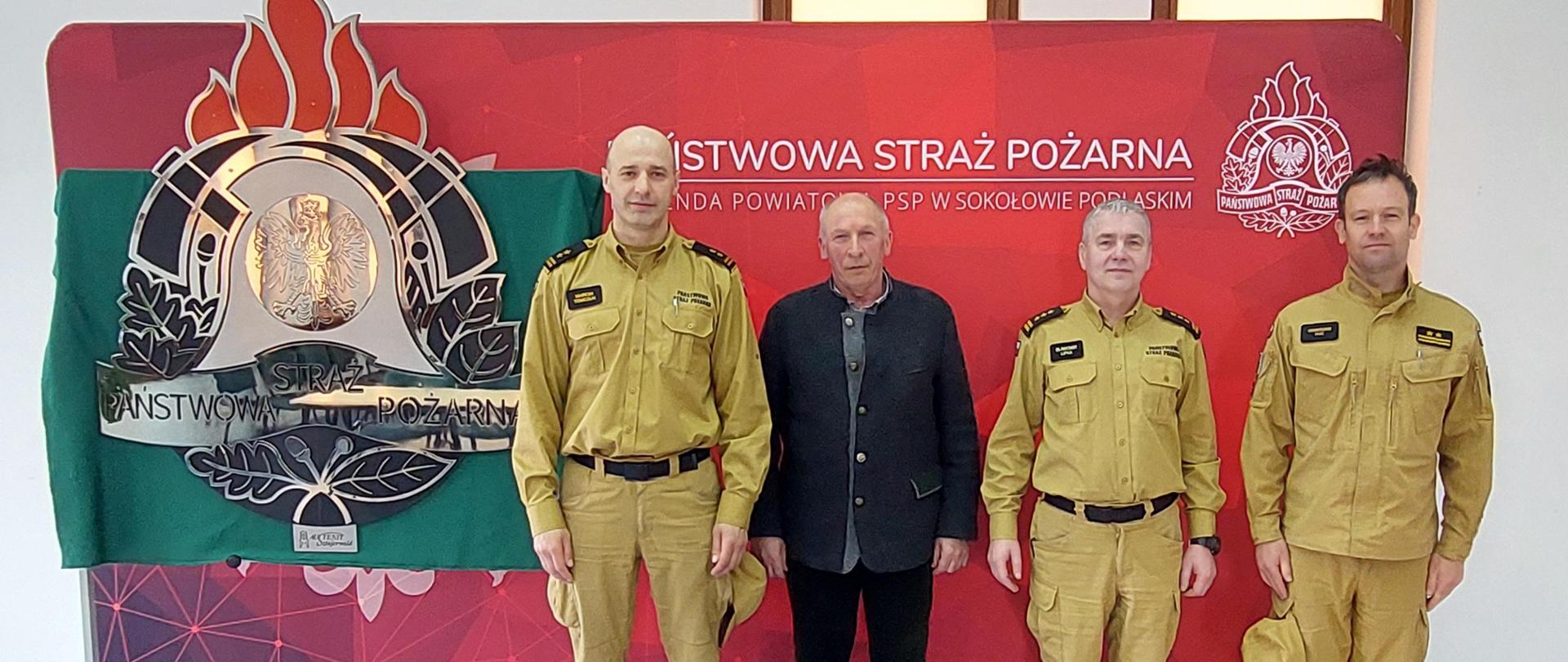 Przekazanie logo PSP dla KP PSP w Sokołowie Podlaskim - zdjęcie w sali w tle baner KP PSP i nowe logo