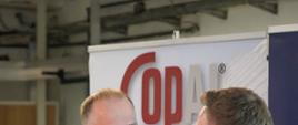na kolorowym tle widoczni 2 mężczyźni 