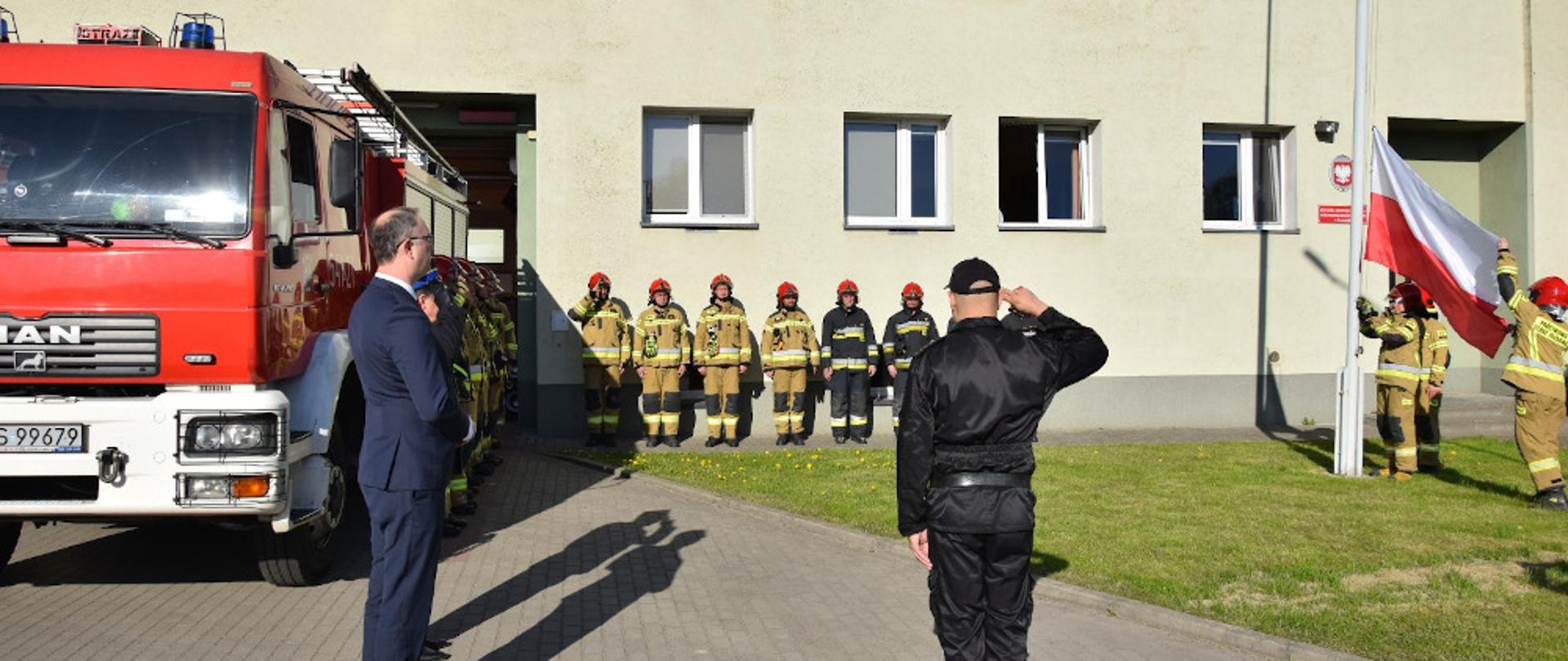 Uroczyste podniesienie flagi państwowej - wicewojewoda zachodniopomorski ubrany w garnitur koloru granatowego, dowódca uroczystości ubrany w ubranie dowódczo-sztabowe koloru czarnego