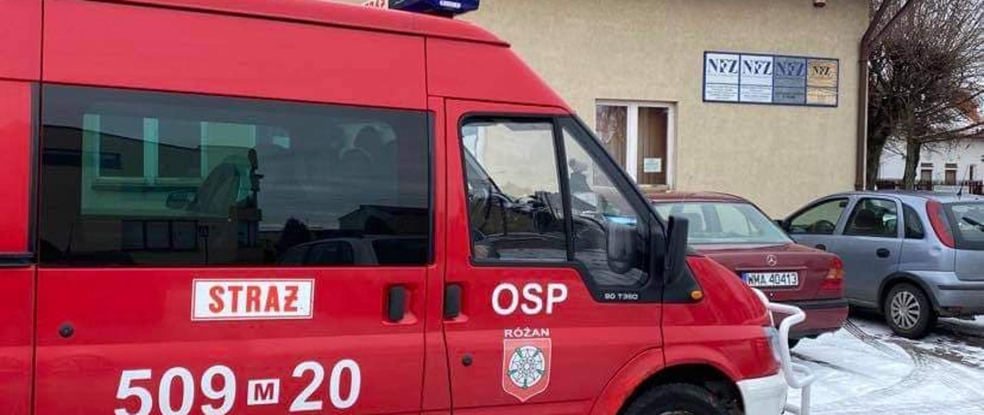 Czerwony samochód strażacki OSP Różan stojący na parkingu przed przychodnią lekarską