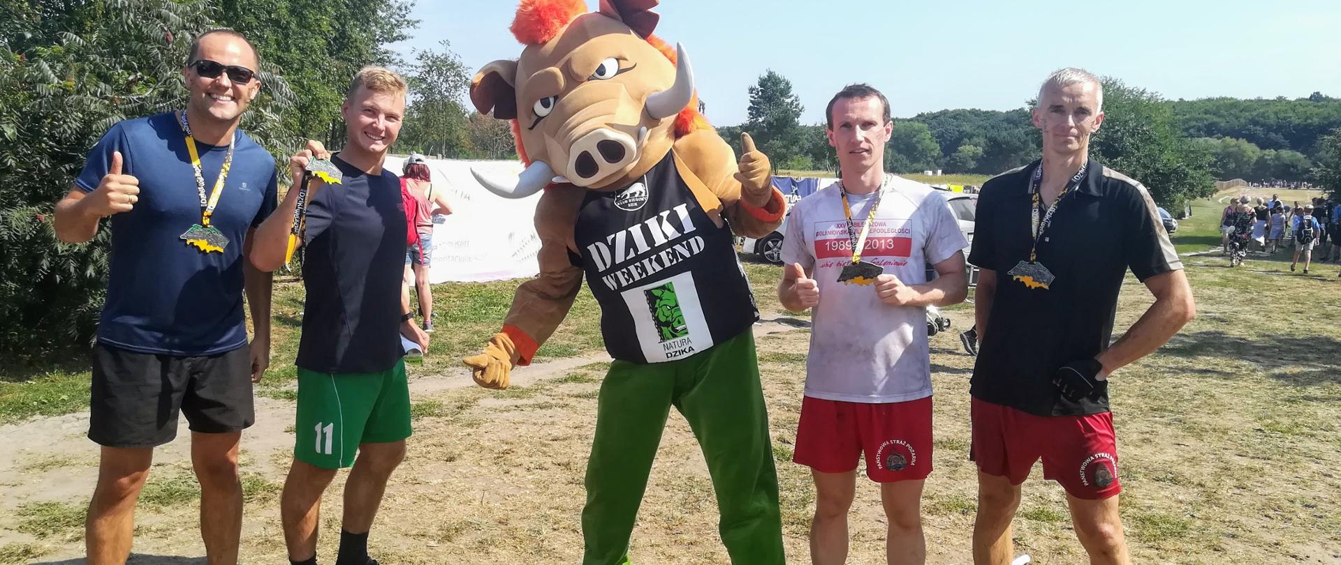 Reprezentanci straży pożarnej z Polic w ubiorach sportowych z maskotką wyścigu