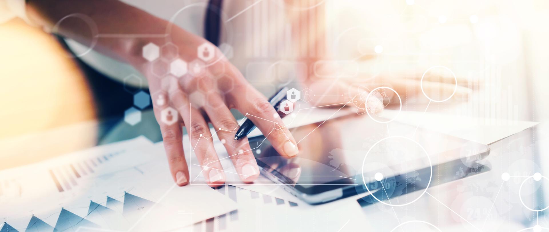 Widać dłoń trzymającą długopis i dotykającą ekran tabletu