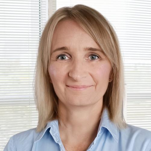 Młoda kobieta z krótkimi blond włosami w niebieskiej koszuli z uśmiechem na twarzy 