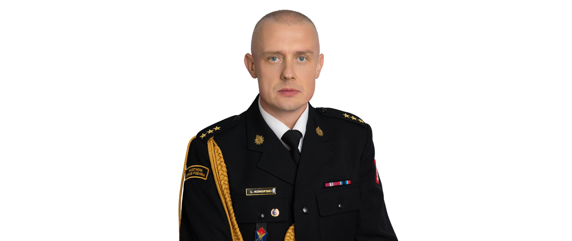 Zdjęcie przedstawia Łukasz Konopskiego, Zastępcę Komendanta Powiatowego Państwowej Straży Pożarnej w Zwoleniu. Jest to portret mężczyzny w mundurze galowym strażaka, z widocznymi dystynkcjami na pagonach. Na piersi munduru widoczne są baretki odznaczeń