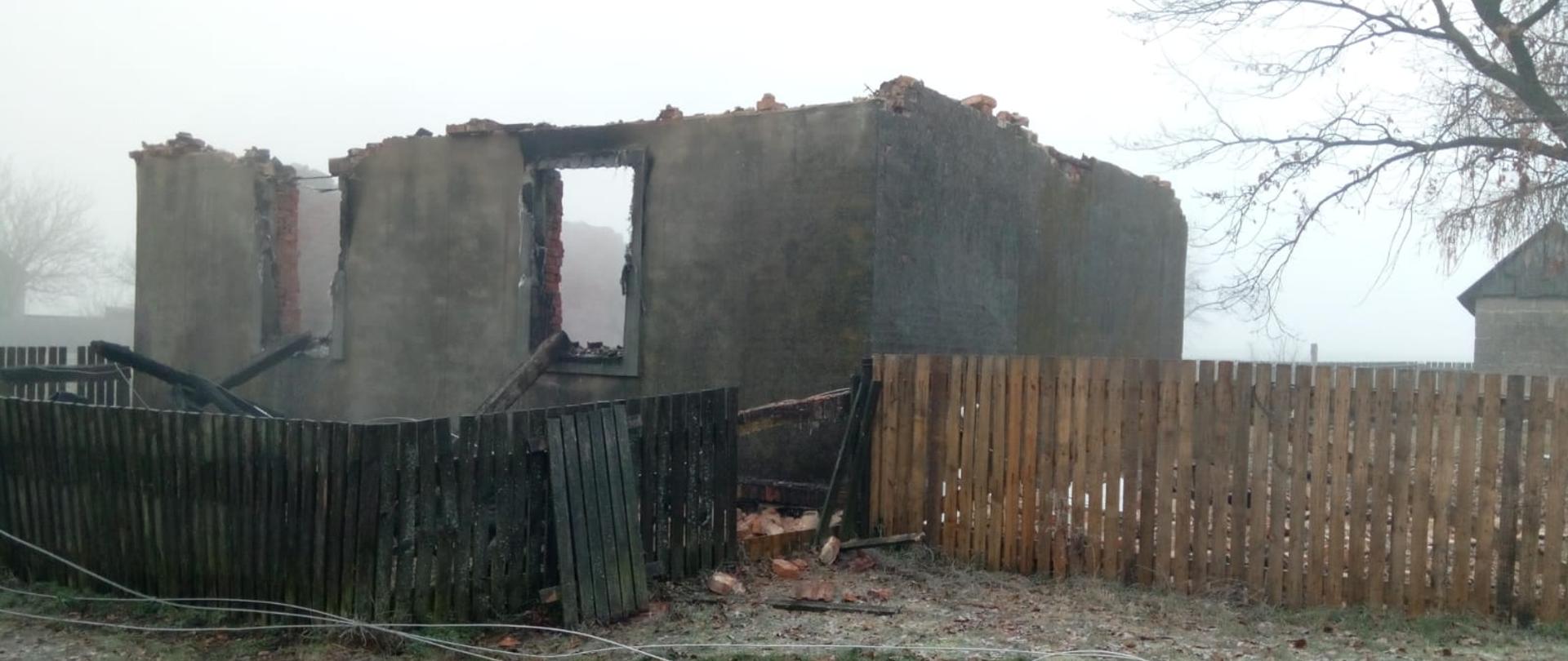 Zdjęcie przedstawia zniszczony przez wybuch i pożar budynek mieszkalny. W wyniku zdarzenia zostały jedynie trzy ściany zewnętrzne.