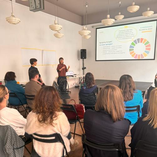 Ludzie siedzą na krzesłach i słuchają osoby prowadzącej szkolenie