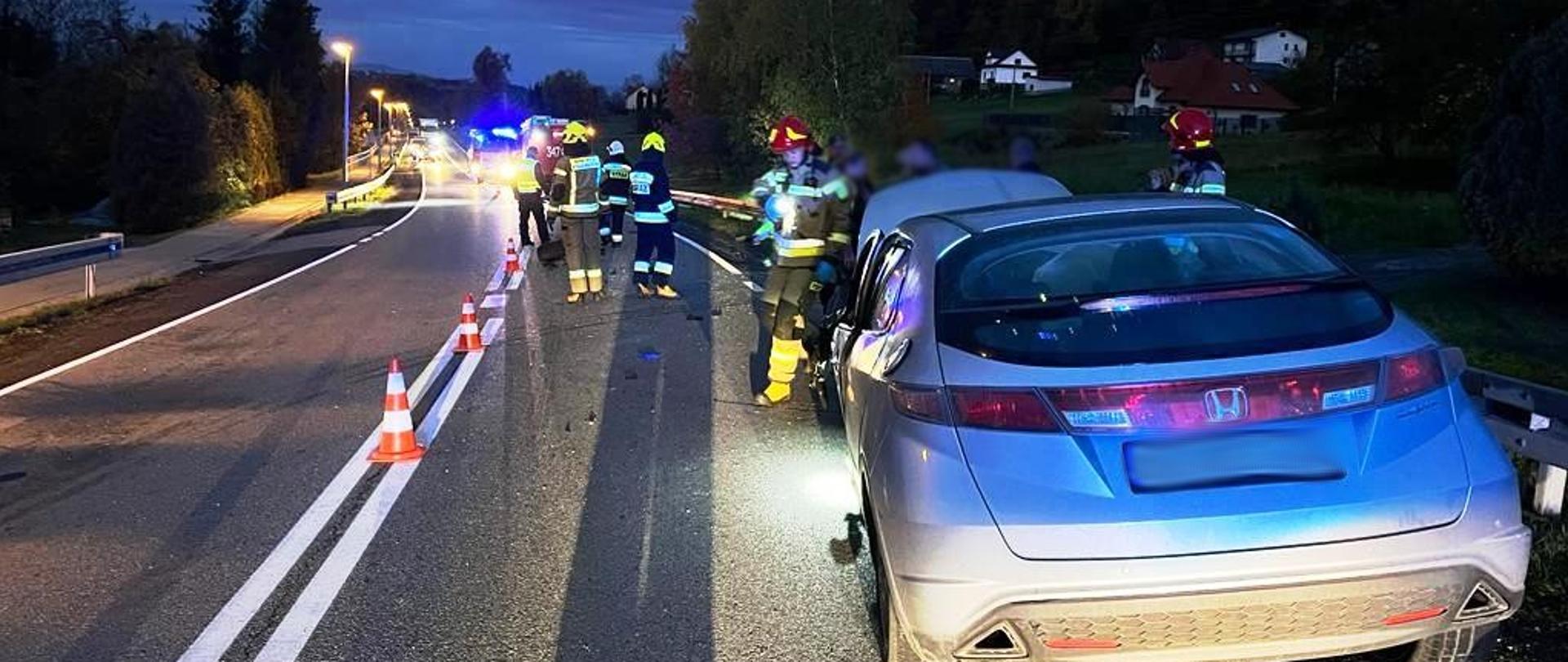 Samochód osobowy na poboczu a bok strażacy.