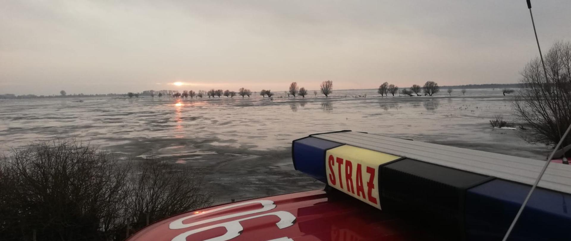 Zdjęcie przedstawia rozlewisko wodne w Parku Narodowym Ujście Warty. Na pierwszym planie dach pojazdu pożarniczego.