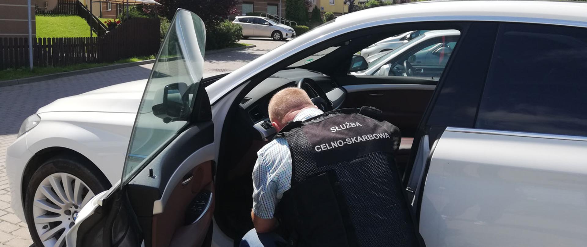 Funkcjonariusz Służby Celno-Skarbowej podczas oględzin zatrzymanego samochodu.