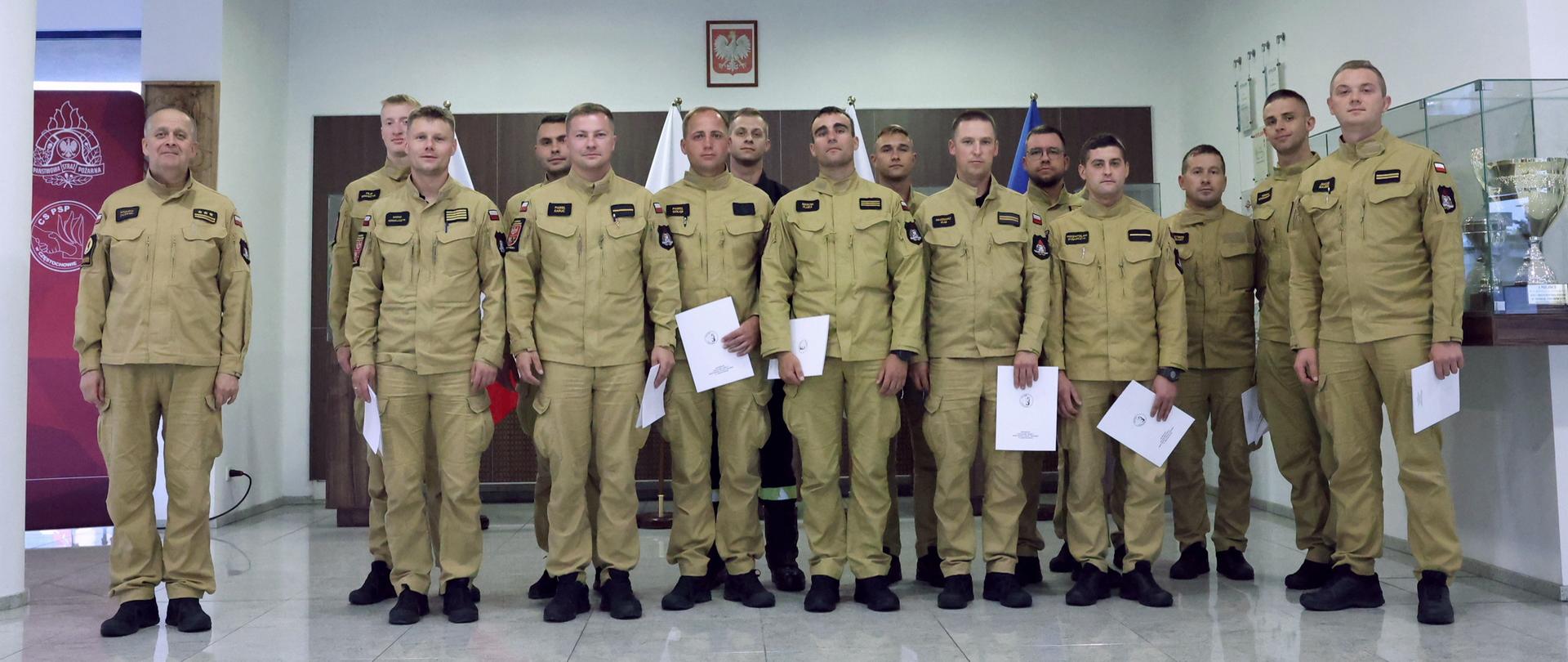 Pamiątkowe zdjęcie grupowe funkcjonariuszy PSP będących uczestnikami szkolenia dla kierowców pojazdów uprzywilejowanych (14 osób) w towarzystwie oficera CS PSP
