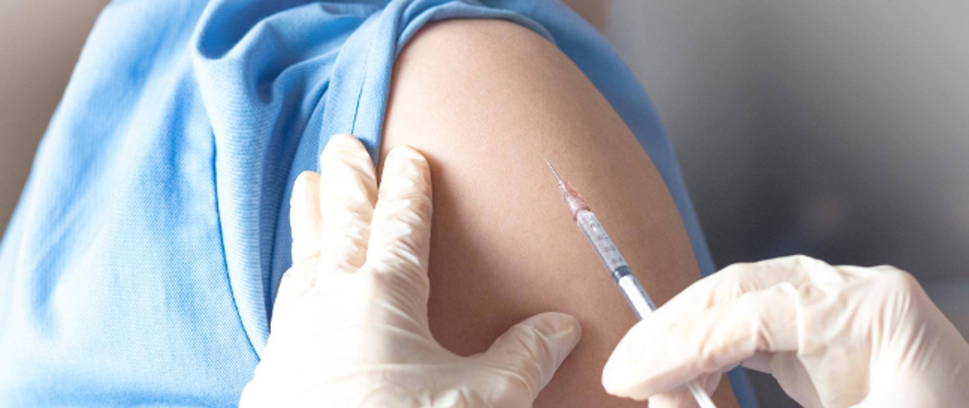 Vaccination healthcare concept. Hands of doctor or nurse in medical gloves injecting a shot of vaccine to a man patient. 