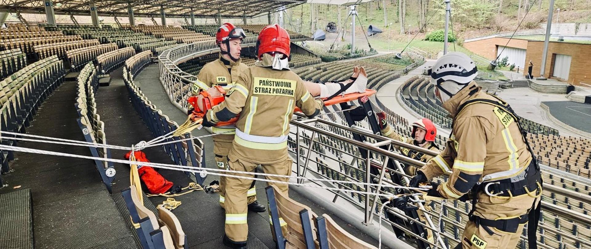 Strażacy za pomocą technik linowych prowadzą ewakuacje poszkodowanego z balkonu.