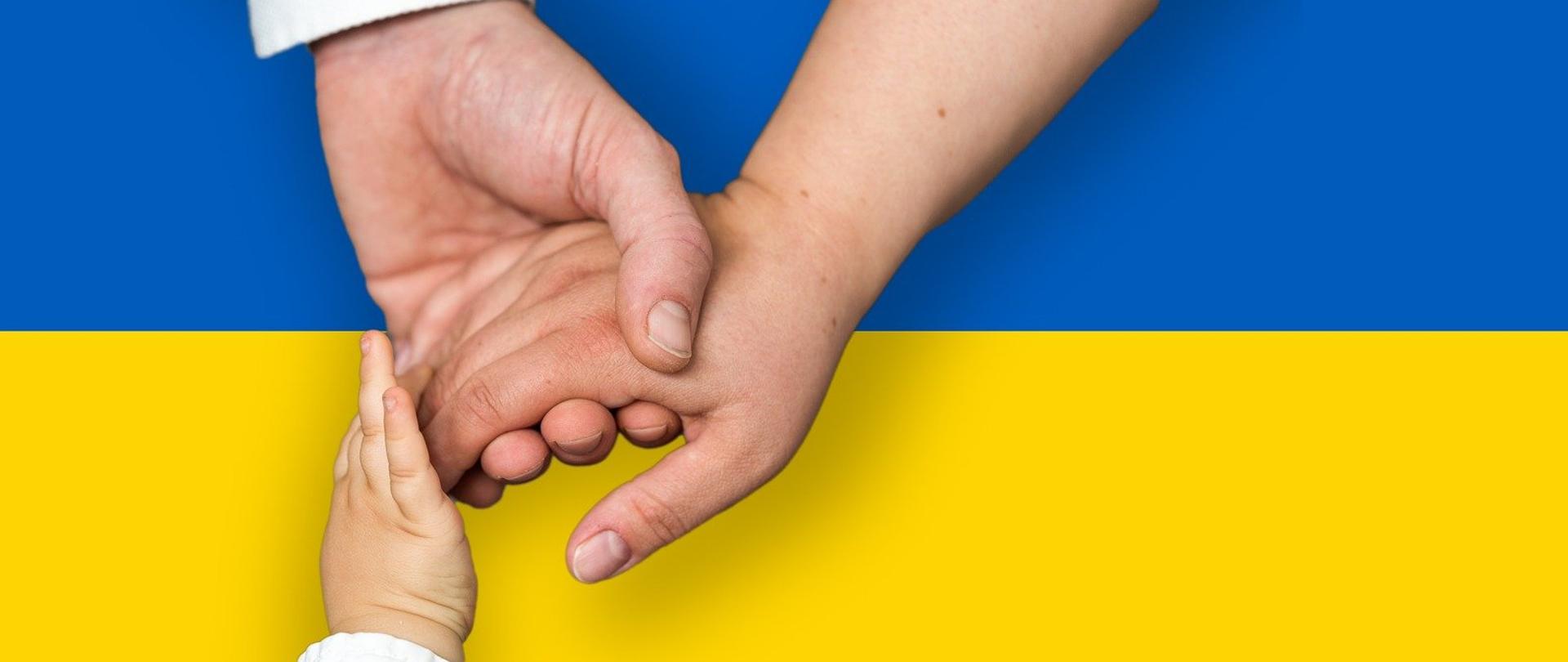 Niebiesko-żółta flaga Ukrainy, dłoń ojca, matki i dziecka w uścisku