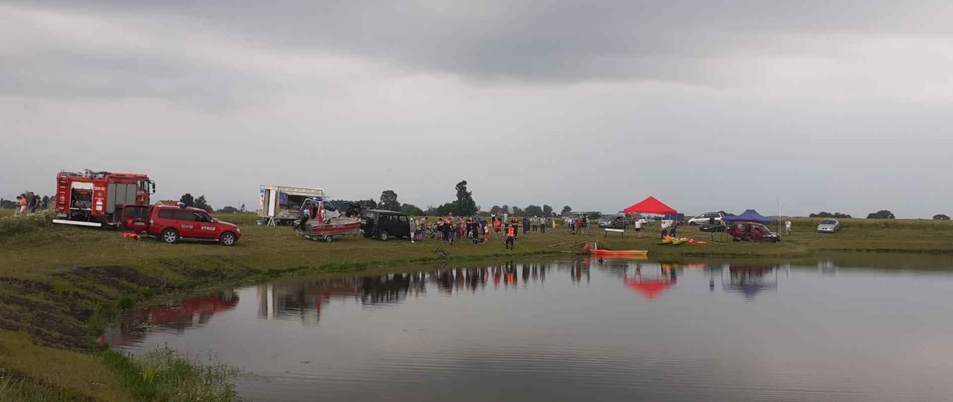 Widok na zbiornik, samochody biorące udział w ćwiczeniach oraz uczestników ćwiczeń.
