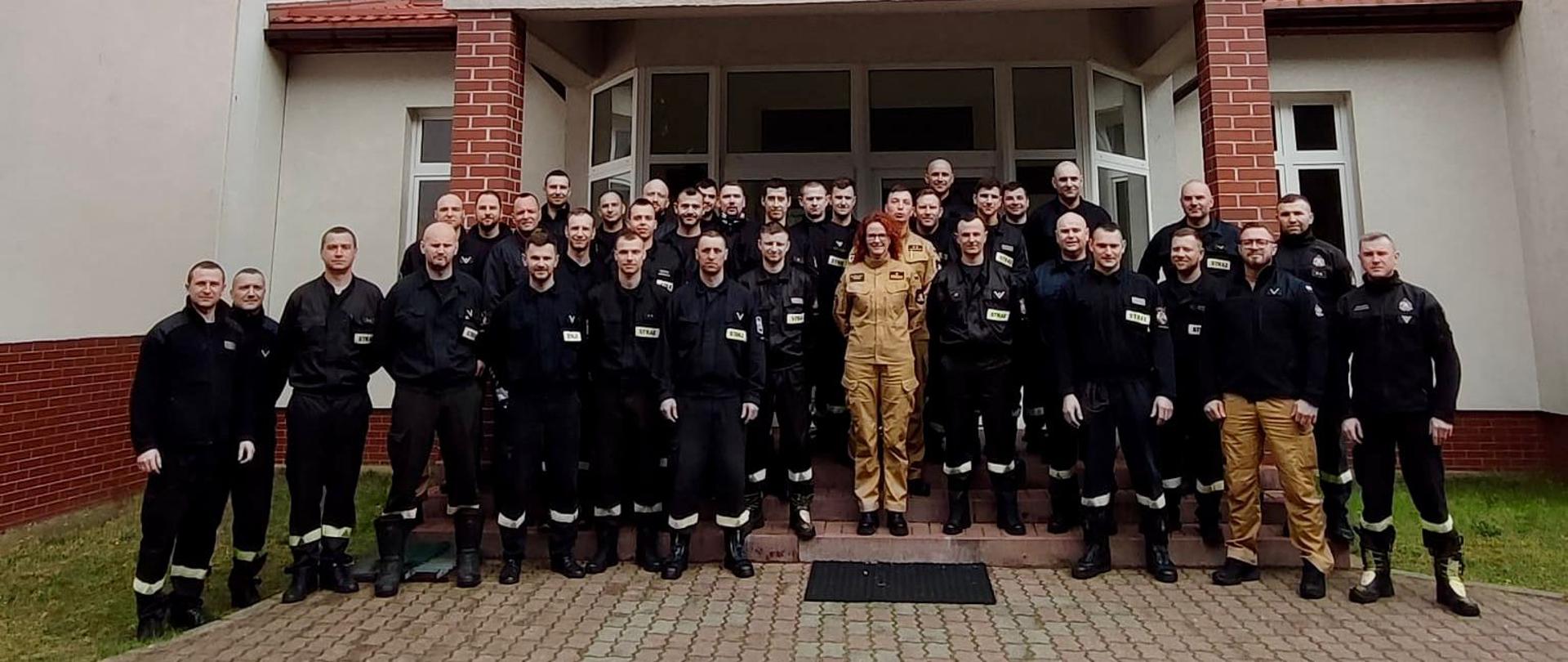 Wspólne zdjęcie strażaków przed ośrodkiem szkolenia.