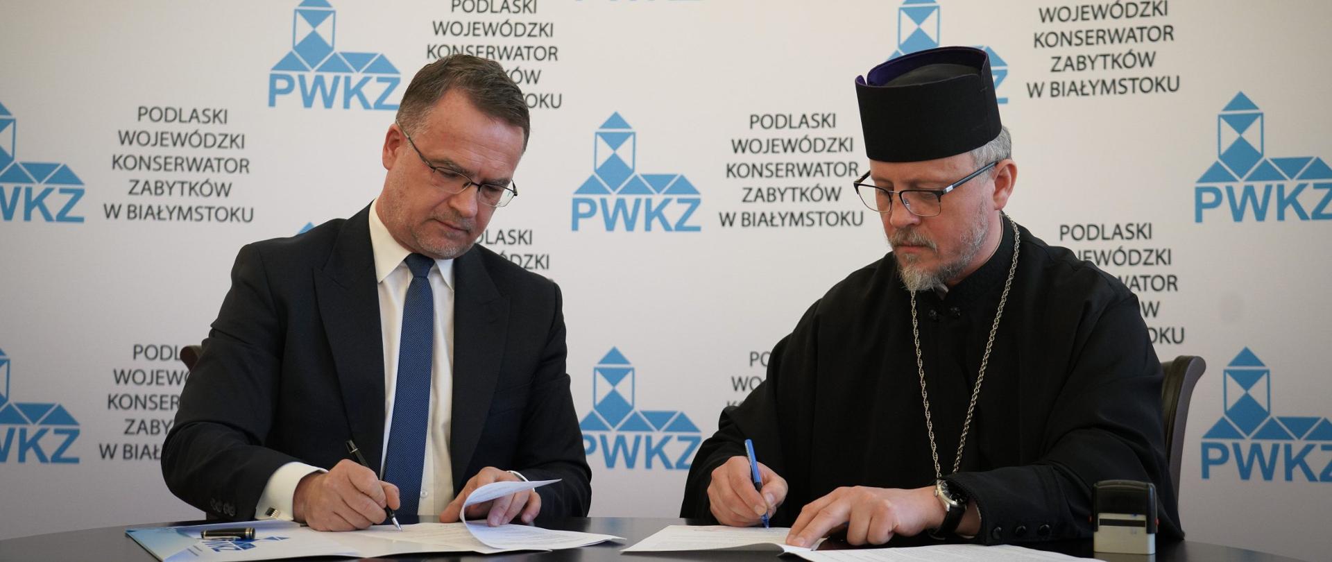 Dwóch mężczyzn podpisujących dokumenty.