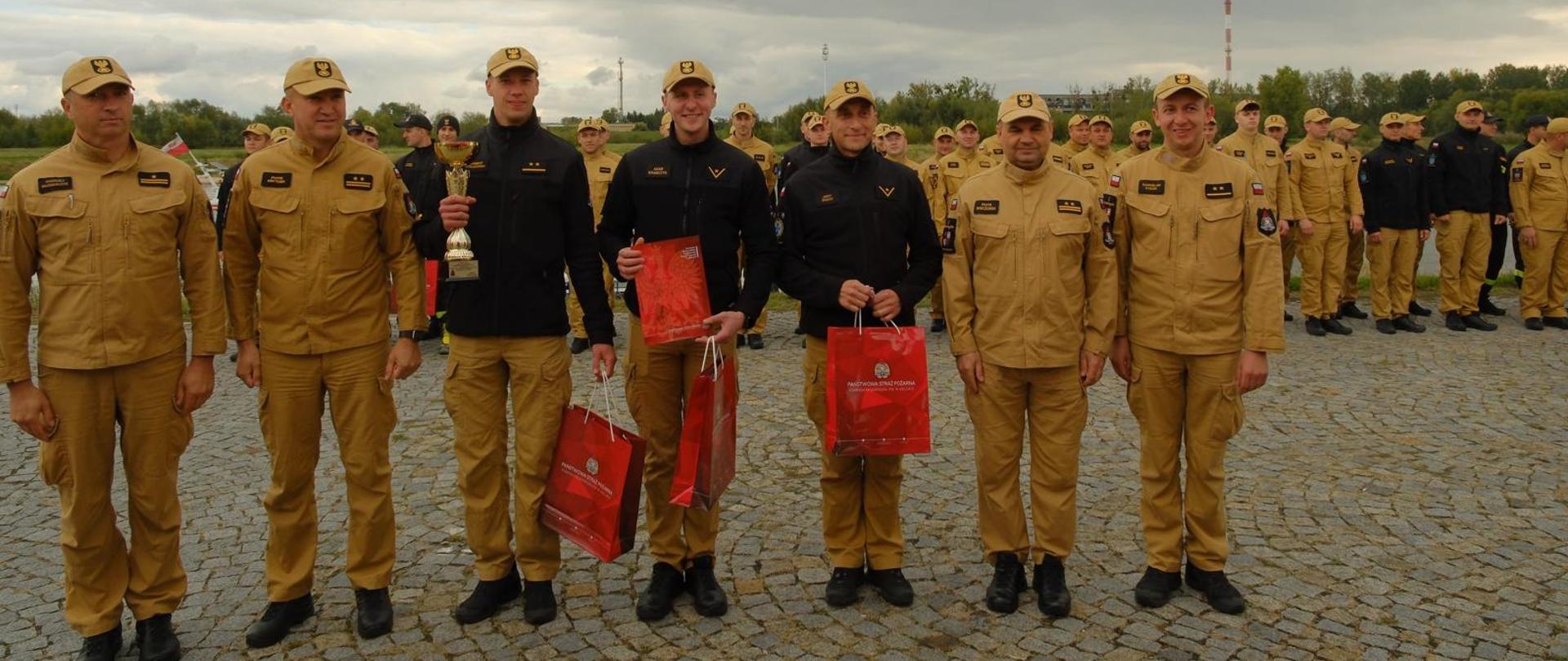 Fotografia przedstawia zwycięską drużynę z Jednostki Ratowniczo-Gaśniczej Nr 1 w Kielcach w towarzystwie Świętokrzyskiego Komendanta Wojewódzkiego PSP, Komendanta Powiatowego PSP w Sandomierzu i jego zastępcy oraz wojewódzkiego koordynatora medycznego.