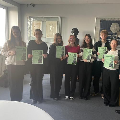 Uczniowie trzymają dyplomy. Za nimi znajduje się czarny fortepian. 