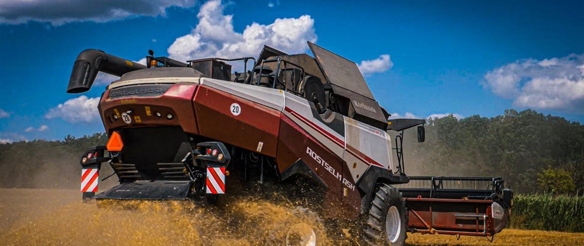 Zdjęcie wykonano porą dzienną w pełnym słońcu na polu kombajn zbożowy marki rostselmash kosi zboże.