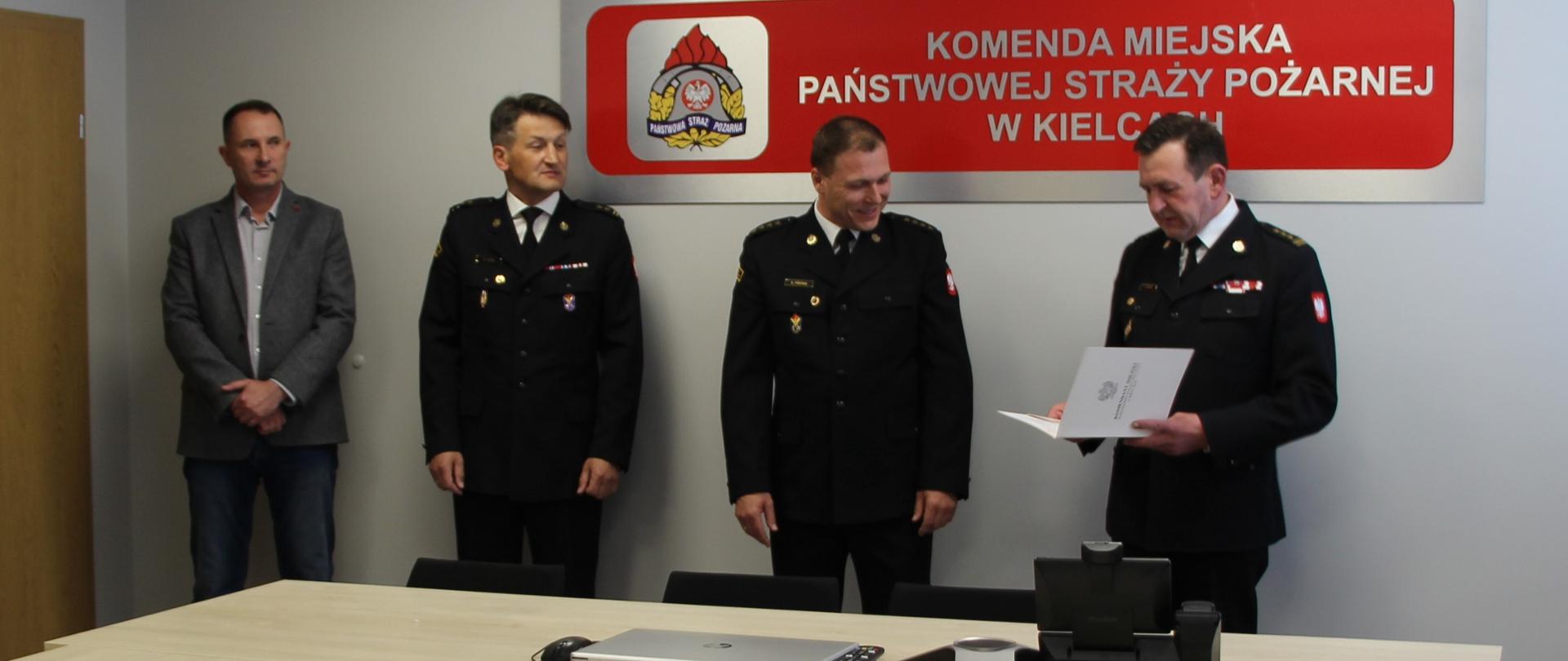 Na zdjęciu przedstawiono chwilę gdy komendant miejski Państwowej Straży Pożarnej w Kielcach st. bryg. Sławomir Karwat odczytuje akt mianowania na naczelnika Wydziału Organizacyjno-Kadrowego st. kpt. Sewerynowi Trepce. Od lewej strony stoją kolejno zastępca komendanta miejskiego PSP st. bryg Marcin Charuba i zastępca komendanta miejskiego PSP bryg Mariusz Góra.