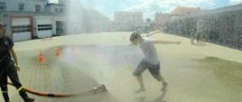 Grodkowska Gra Miejska - zdjęcie przedstawia uczestnika gry miejskiej przebiegającego przez kurtynę wodną wodną 