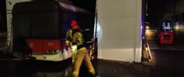 Strażacy podczas wydobywania autobusu z budynku myjni. Pora nocna. 