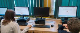 uczniowie przy monitorach