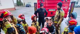 Zdjęcie przedstawia strażaków oraz dzieci podczas pokazu w związku z akcją "Bezpieczne Ferie"