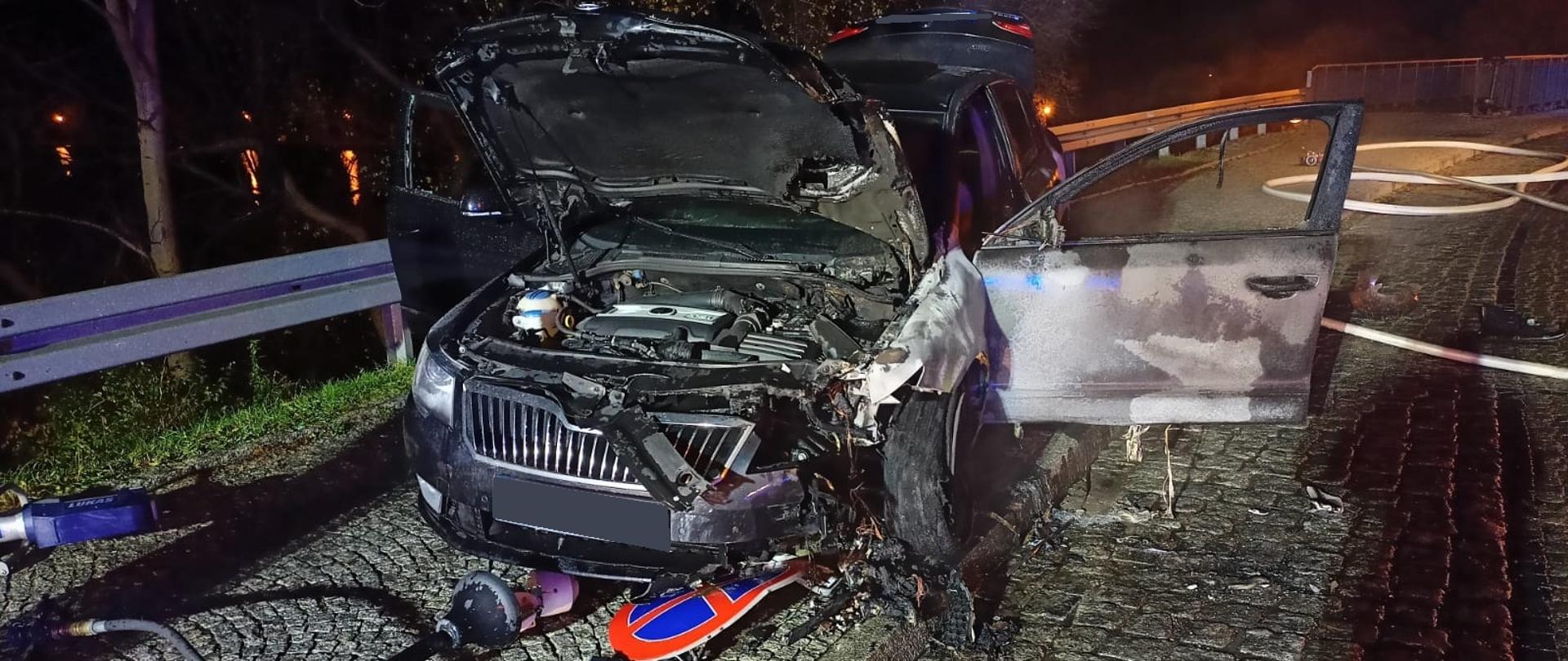 na zdjęciu widać częściowo spalony samochód osobowy, uszkodzoną latarnię