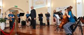 Wykonawcy przy instrumentach na scenie w sali koncertowej podczas Koncertu końcoworocznego wpisującego się w szmaragdowy Jubileusz lublinieckiej szkoły muzycznej