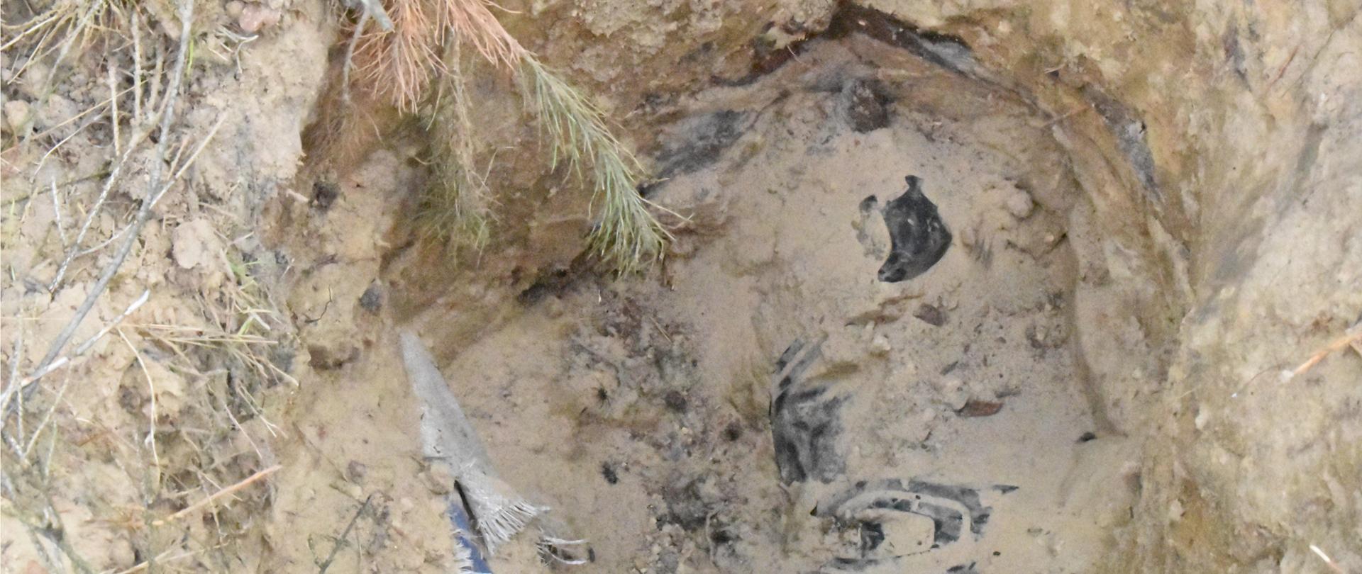 Niewielki wykop w ziemi. W dole znajdują się odpady pochodzące z gospodarstw rolnych.