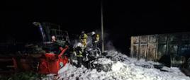 Jest noc, widać strażaków jak gaszą pożar opon i kombajn
