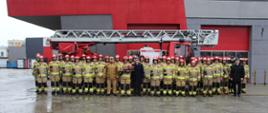 Na zdjęciu widzimy pamiątkowe ustawienie strażaków z Jednostki Ratowniczo-Gaśniczej nr 1 w Kielcach, którzy wraz z Komendantem Miejskim PSP w Kielcach zegnają wieloletniego kolegę odchodzącego na emeryturę.