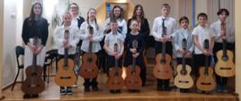 Galeria 18 zdjęć z Wiosennego Koncertu Gitarowego uczniów klas gitary A. Kozakowskiej i W. Kozakowskiego - 22 marca 2024. Uczestnicy konkursu grają na gitarze na scenie auli PSM w Kłodzku