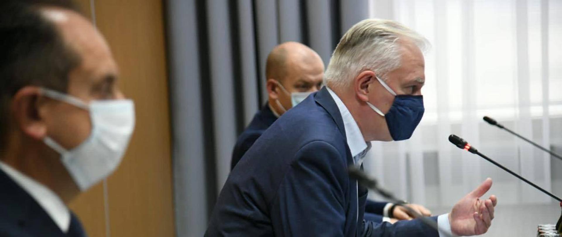 Jarosław Gowin widziany z profilu. Obok niego Andrzej Gut-Mostowy. Siedzą przy stole, przed nimi mikrofony.