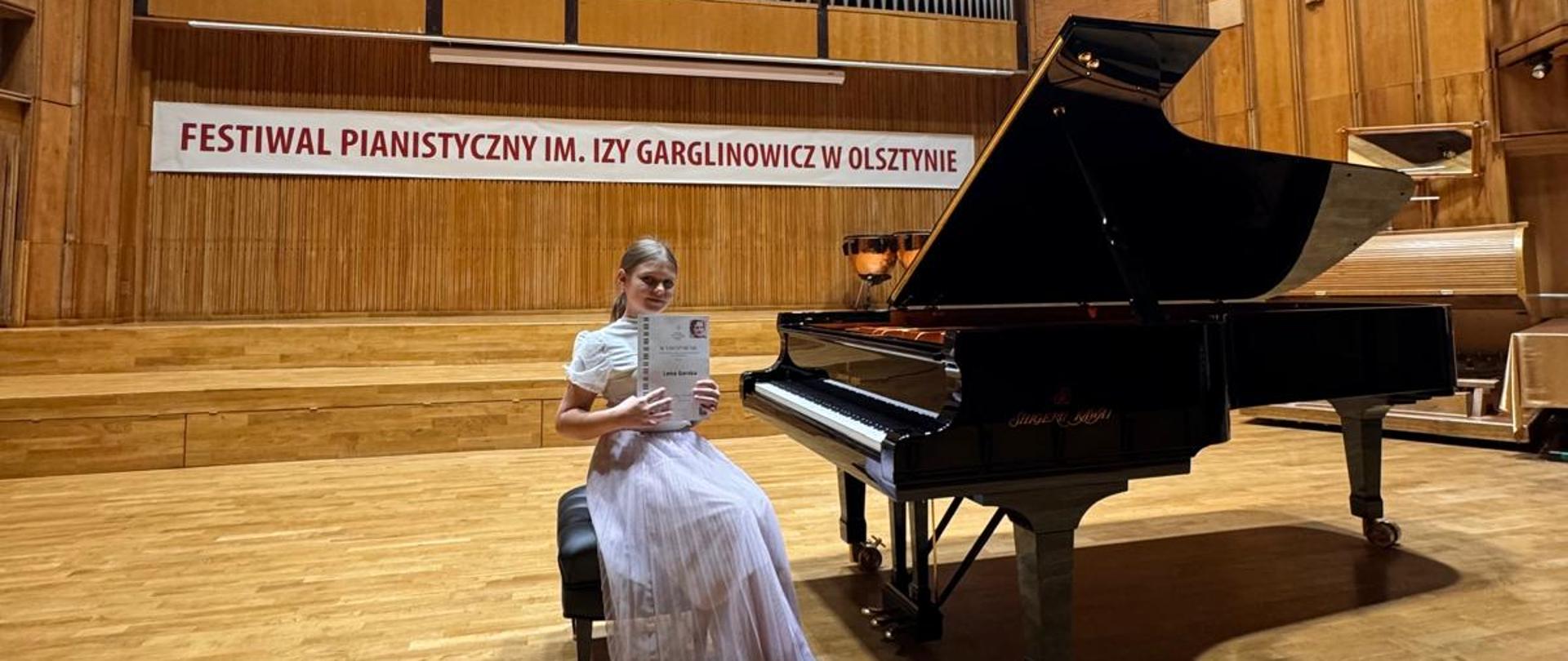 na scenie uczennica trzymająca dyplom