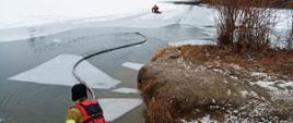Na zdjęciu strażacy ćwiczą na zalodzonym zbiorniku wodnym