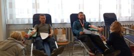 Na zajęciu widoczni dwaj mężczyźni siedzący na fotelach na sali oddający krew podczas akcji zbiórki krwi zorganizowanej przez Kluby Honorowych Dawców Krwi Polskiego Czerwonego Krzyża przy Komendzie Powiatowej Państwowej Straży Pożarnej w Gorlicach i Klub Honorowych Dawców Krwi Polskiego Czerwonego Krzyża Moszczenica