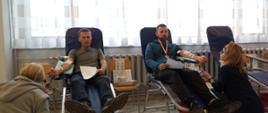 Na zajęciu widoczni dwaj mężczyźni siedzący na fotelach na sali oddający krew podczas akcji zbiórki krwi zorganizowanej przez Kluby Honorowych Dawców Krwi Polskiego Czerwonego Krzyża przy Komendzie Powiatowej Państwowej Straży Pożarnej w Gorlicach i Klub Honorowych Dawców Krwi Polskiego Czerwonego Krzyża Moszczenica