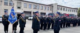 Zdjęcie przedstawia moment składania meldunku przez dowódcę uroczystości kpt. Bartosza Lisowskiego dla Zastępcy Komendanta Wojewódzkiego PSP we Wrocławiu st. bryg. Bogusława Bruda. W tle widoczny jest Komendant Powiatowy PSP w Lwówku Śląskim st. bryg. Mariusz Mróz, poczet sztandarowy oraz strażacy. 